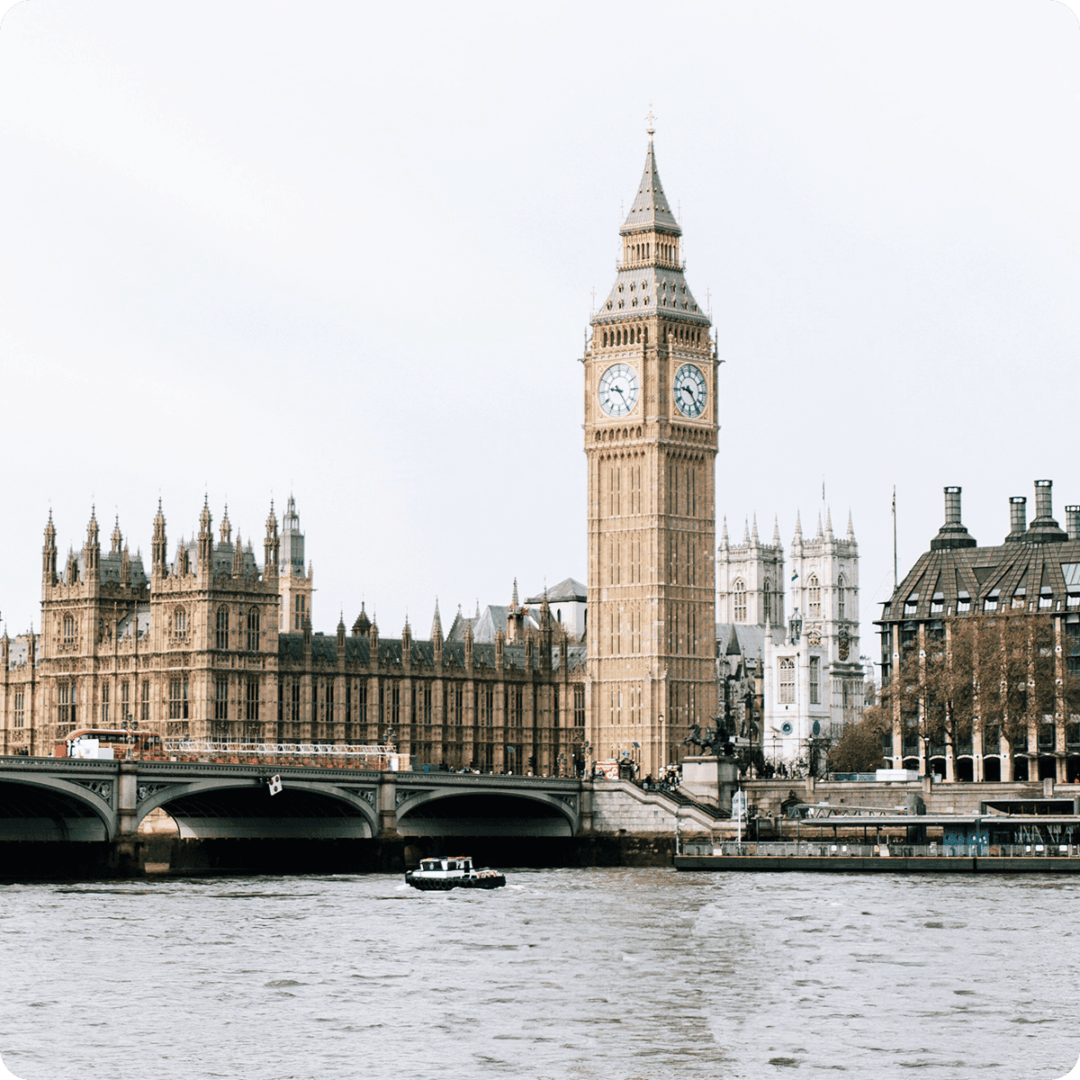 View of Big Ben and the Houses of Parliament from across the River Thames, with a small boat on the water.