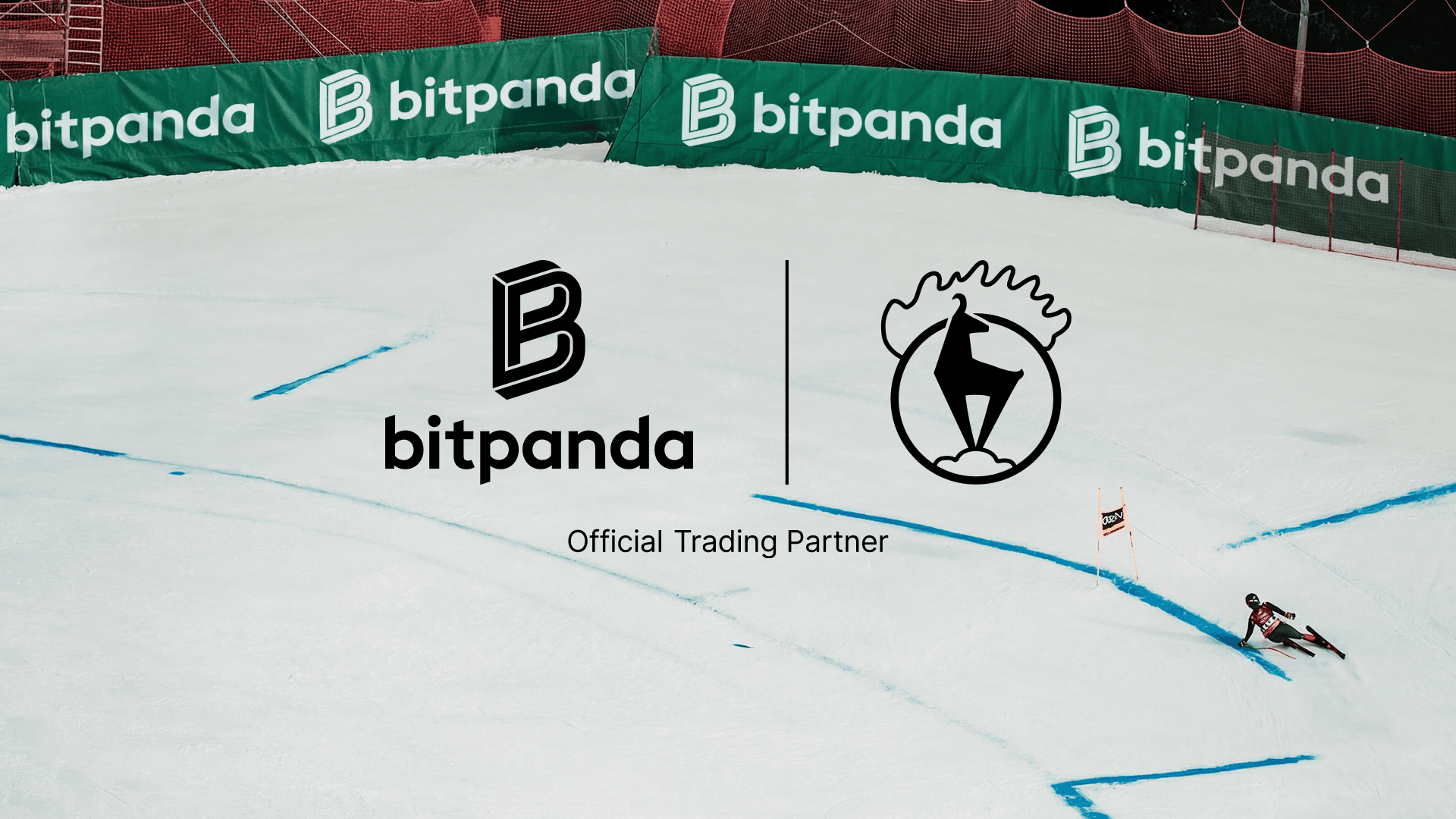 A skier descends a snowy slope with Bitpanda logos on surrounding barriers, indicating sponsorship or partnership.