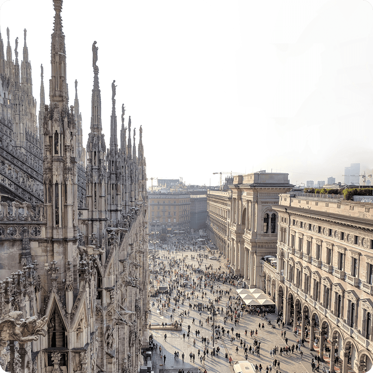 Aerial view of Milan's Piazza del Duomo, featuring the cathedral's ornate spires and bustling crowds below in the square.