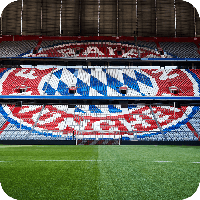 Soccer stadium with empty seats forming a red, white, and blue emblem design, green field in the foreground, and a goalpost in the center.