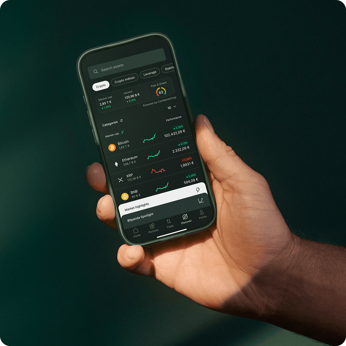 A hand holds a smartphone displaying a cryptocurrency tracking app with various coin prices, charts, and market trends on a dark background.