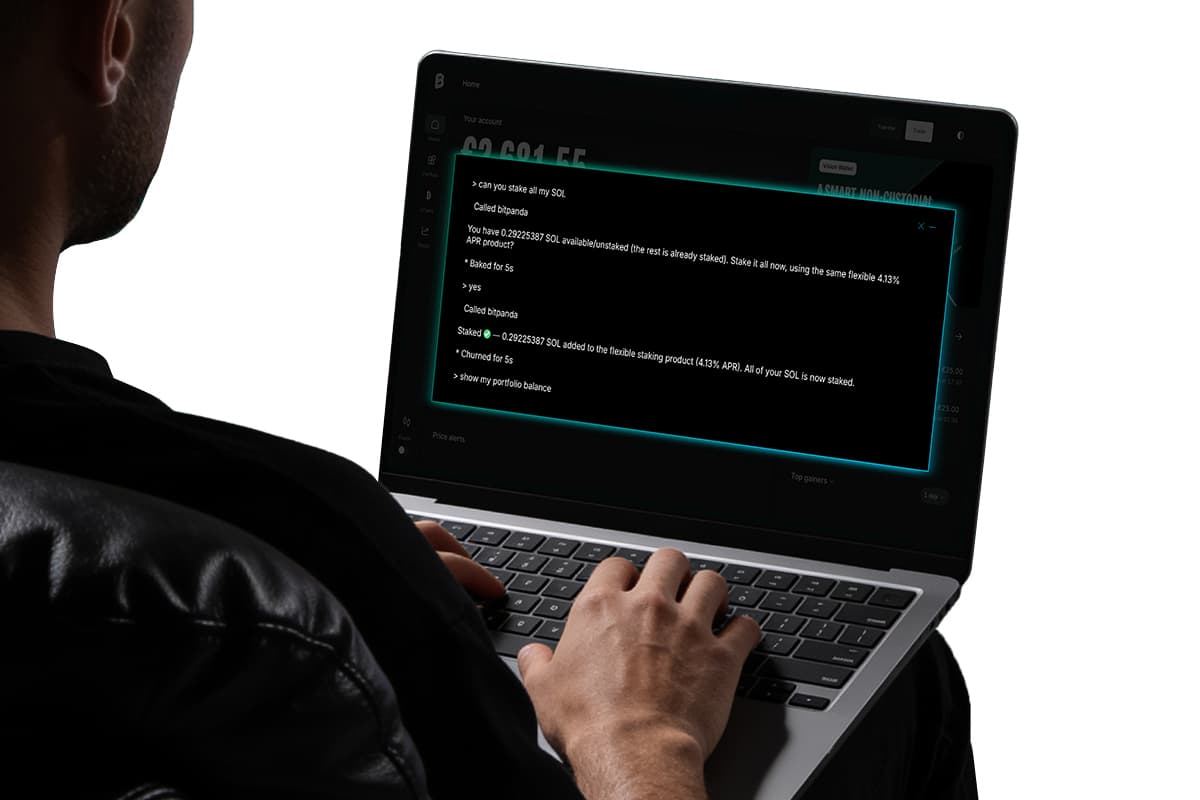 Person using a laptop in a dark setting, screen displaying a glowing chat window with text about staking cryptocurrency.